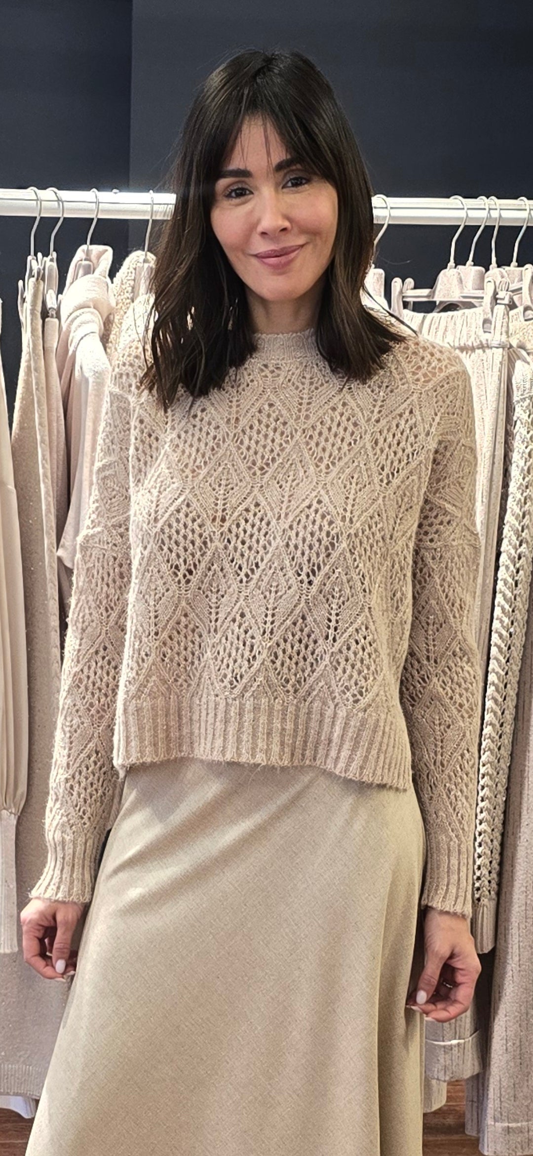 Woman wearing a beige knitted sweater and skirt in a clothing store.